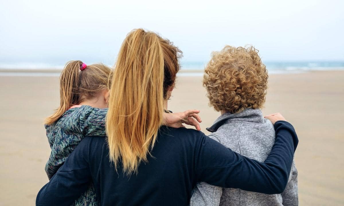 Back view of three generations female looking at sea on the beach in autumn