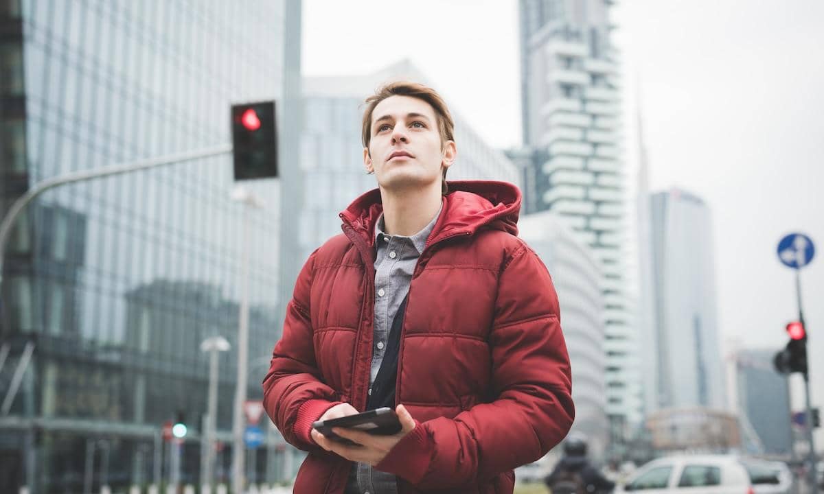 Half lenght of a young handsome caucasian contemporary businessman walking through the city using a tablet overlooking - technology, network, business, finance concepts