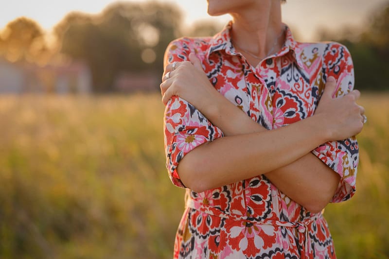 young woman embracing herself, self-love in action, mental health advocate, practicing self-care for finding inner peace, in European countryside