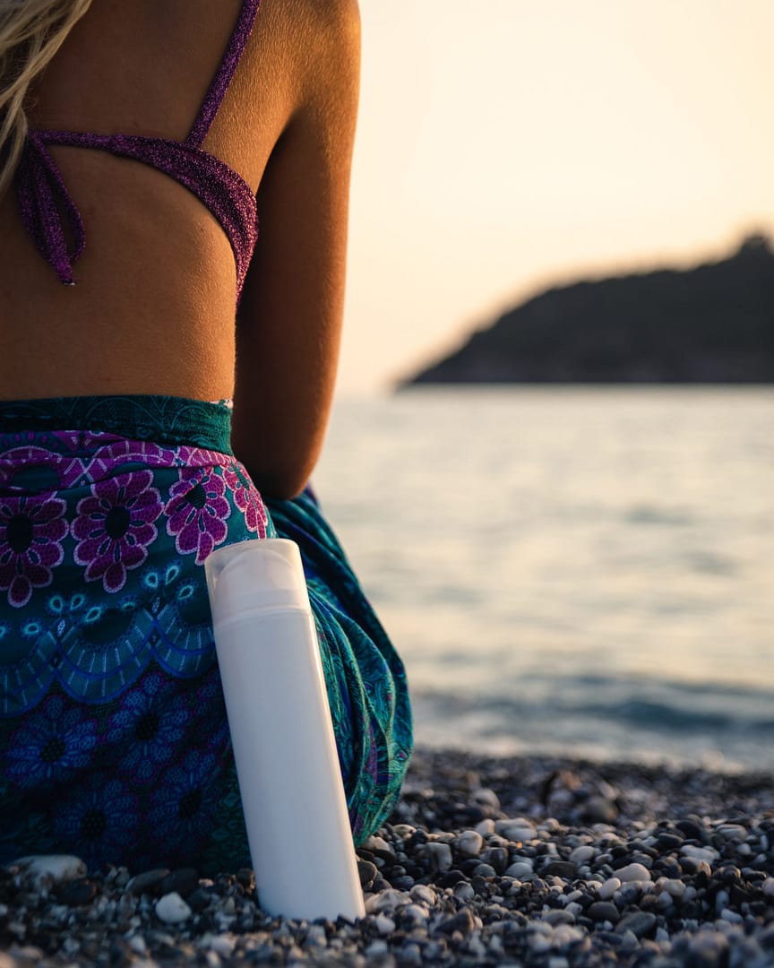 Woman & a bottle of sunscreen at the beach
